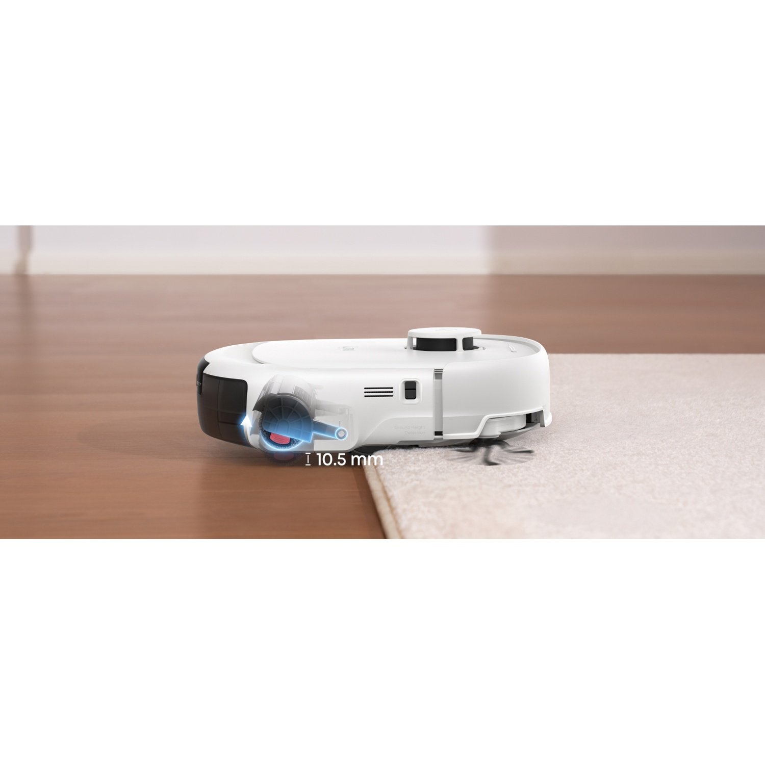 Un aspirateur robot blanc sur un tapis à côté d'un parquet.