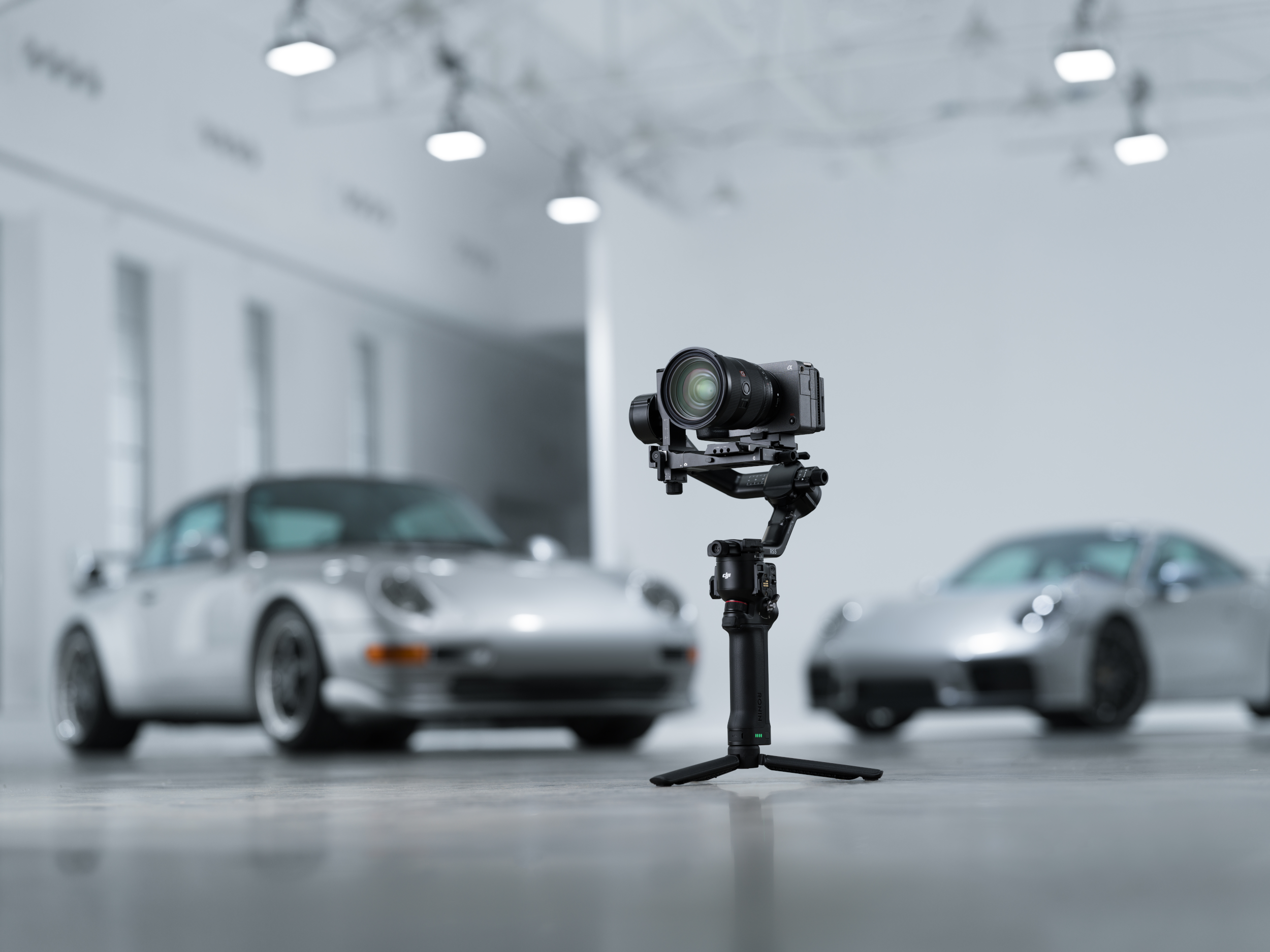 Un cardan avec caméra devant deux Porsche argentées.