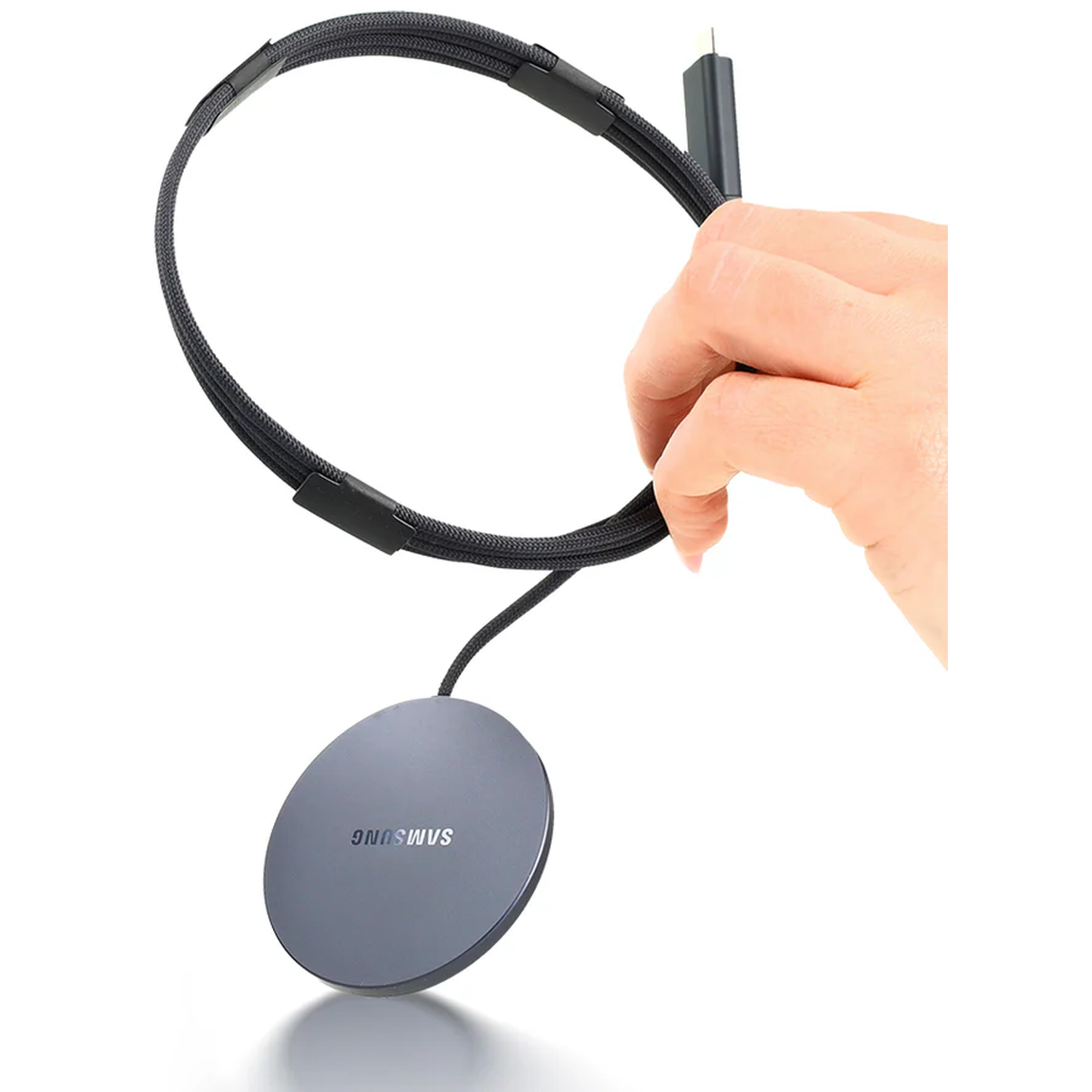 Een hand houdt een zwarte kabel vast die is aangesloten op een ronde Samsung-oplader.