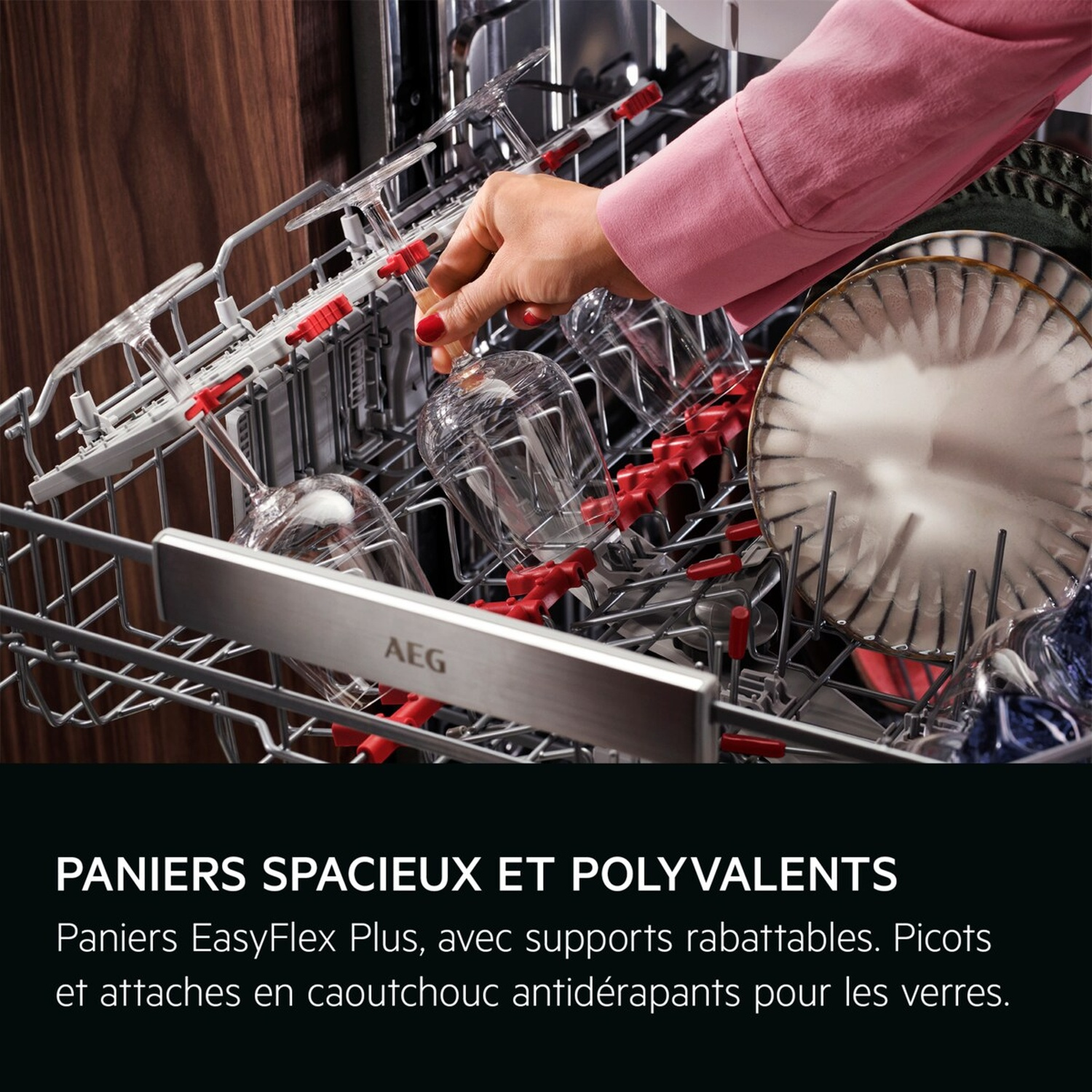 Une personne charge des verres à pied transparents et des assiettes blanches dans un lave-vaisselle AEG, montrant des paniers flexibles et des supports en caoutchouc rouge.