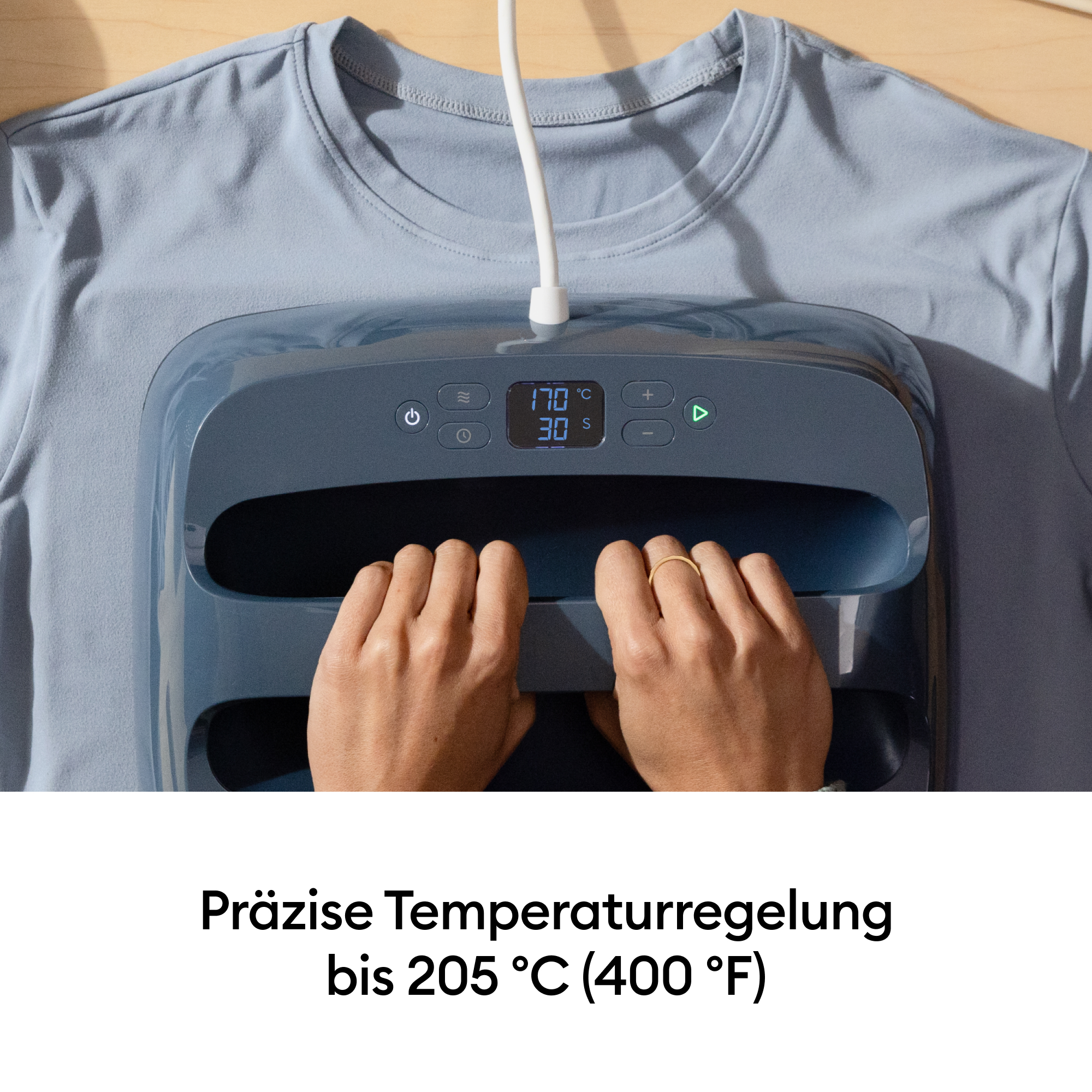 Hände bedienen eine Heizpresse, die auf einem blauen T-Shirt liegt. Temperatur 170°C, Zeit 30s.