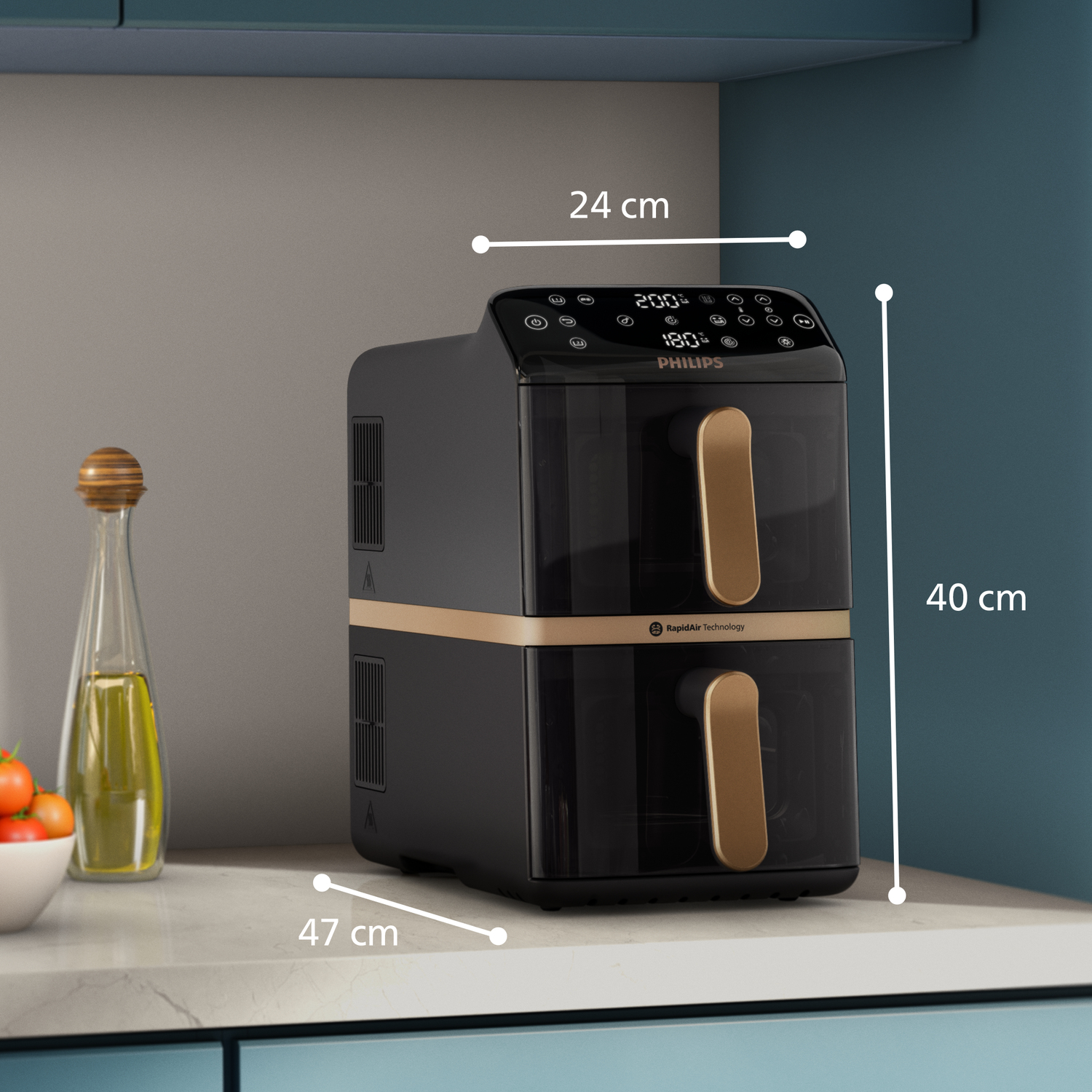 Czarna frytkownica beztłuszczowa Philips z dwiema szufladami, obok butelka oliwy i miska pomidorów.