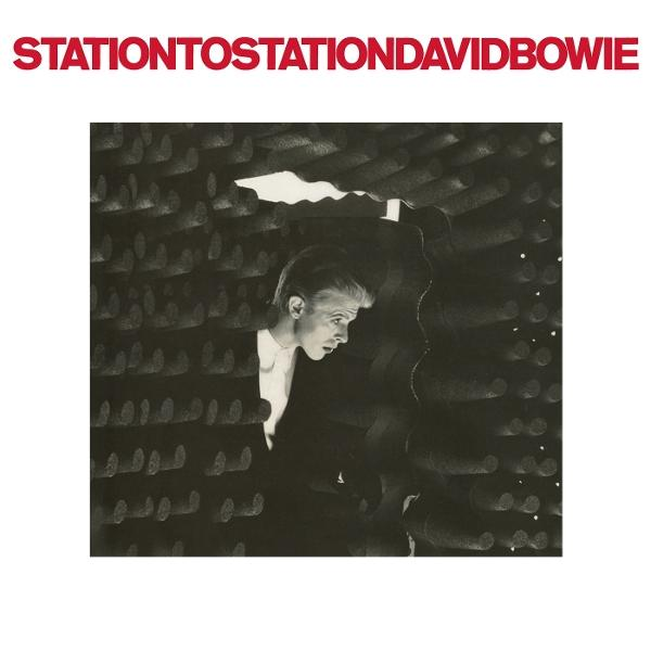 David Bowie mit Anzug vor dunkler, texturierter Wand. Titel oben.