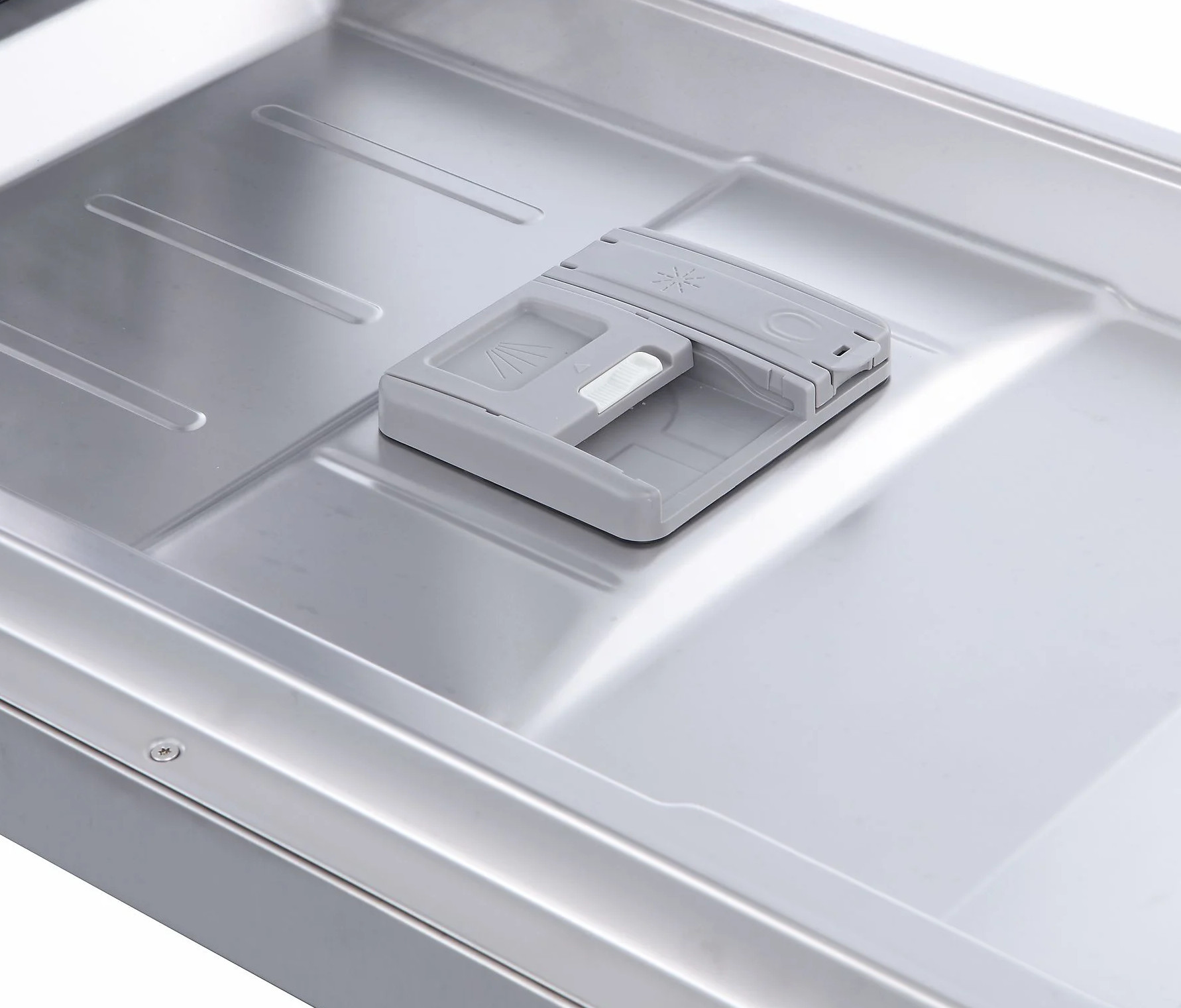 Szary dozownik detergentu znajduje się na podstawie ze stali nierdzewnej zmywarki.