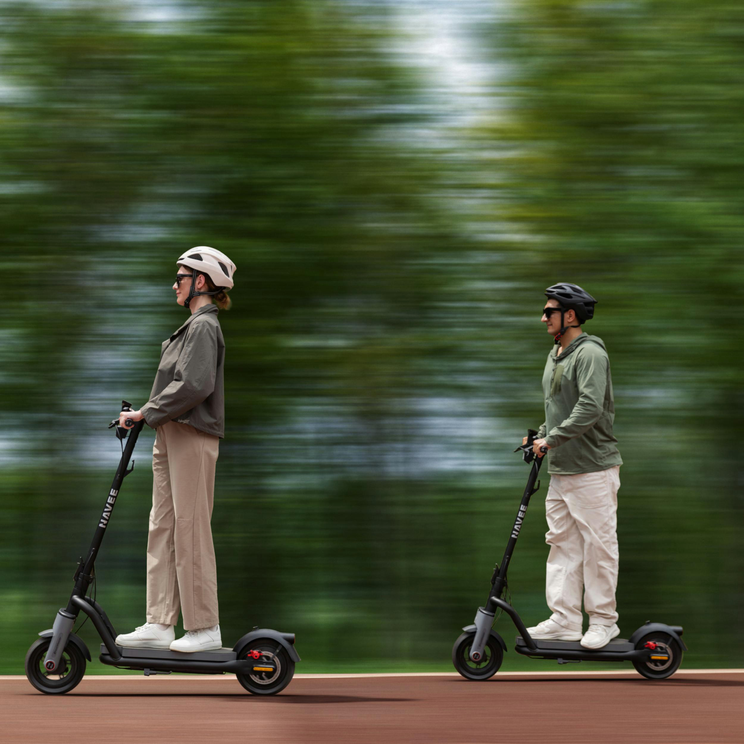 Zwei Personen fahren E-Scooter vor einem verschwommenen grünen Hintergrund.