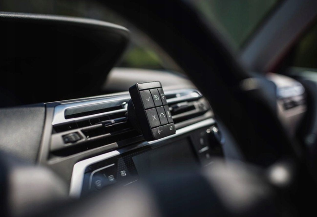 Czarny kontroler z przyciskami znajduje się na nawiewie samochodowym.
