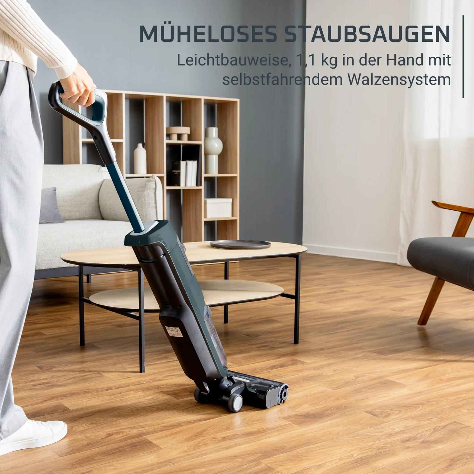Eine Person benutzt einen leichten Staubsauger im Wohnzimmer auf Holzboden.