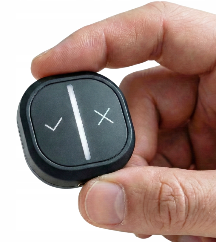 Dłoń trzyma małe czarne urządzenie ze znakiem zaznaczenia i krzyżykiem.