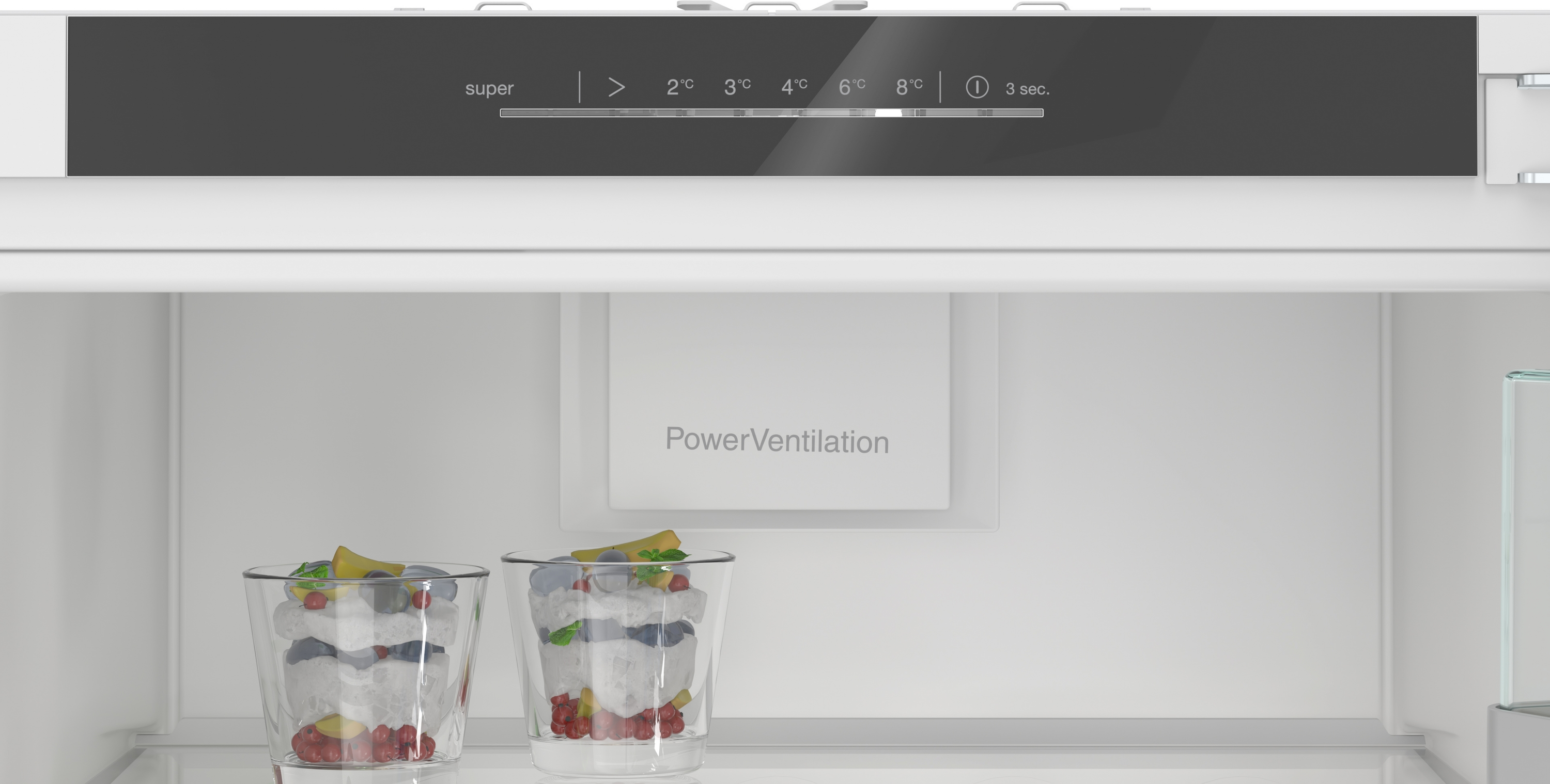 Zwei Gläser mit Schichten aus Obst und Sahne stehen in einem Kühlschrank.
