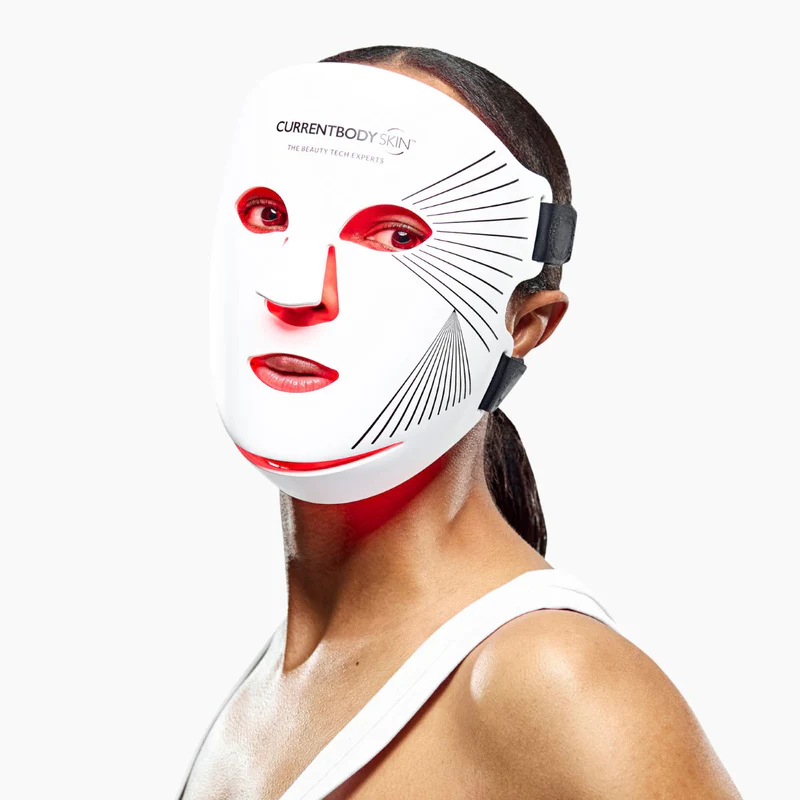 Una mujer usa una mascarilla facial LED blanca con luces rojas.