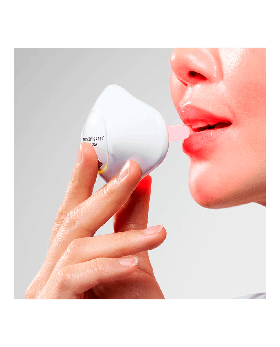 Una mano sostiene un dispositivo blanco en los labios de una persona.