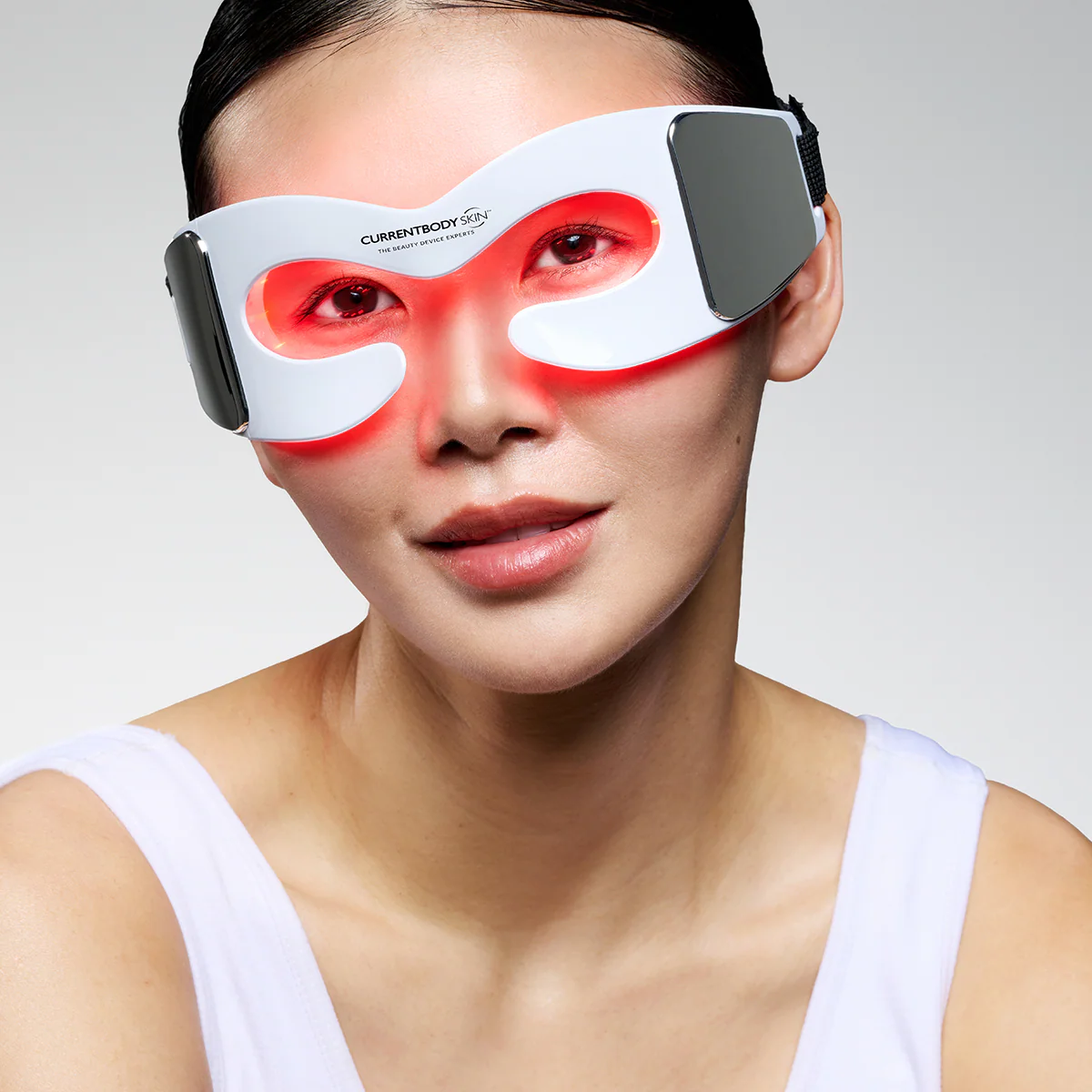 Una mujer usa una máscara de ojos LED blanca con luces rojas.