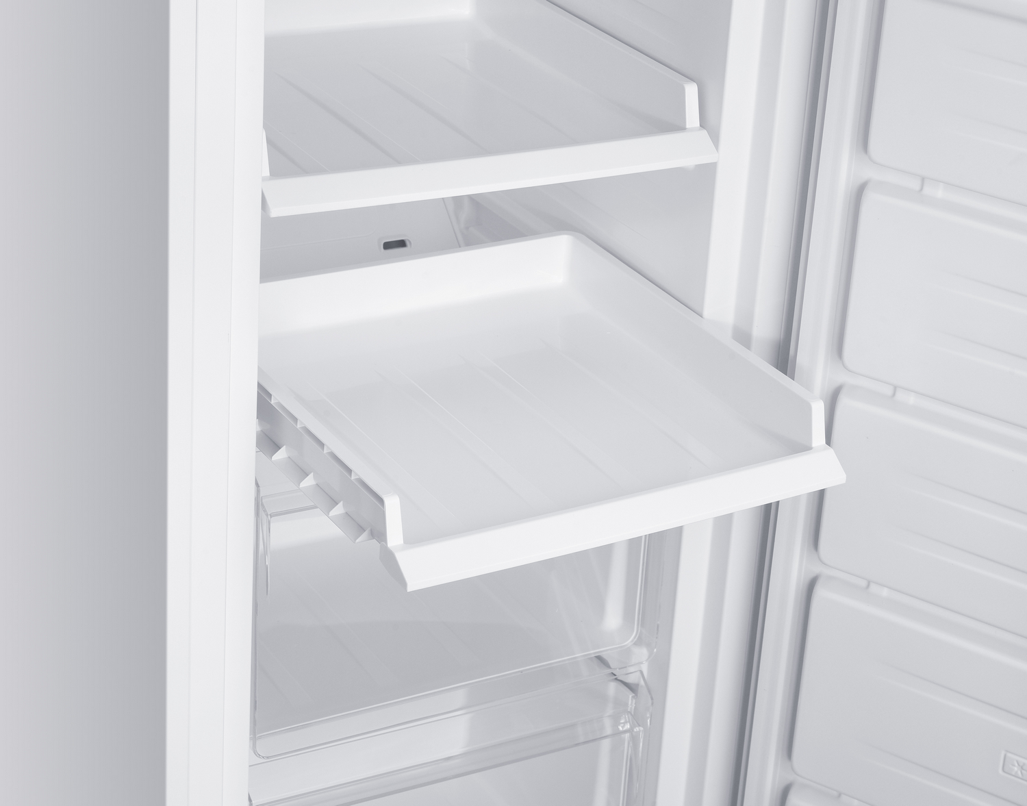 Interior de un refrigerador blanco con cajón extraíble y estantes.