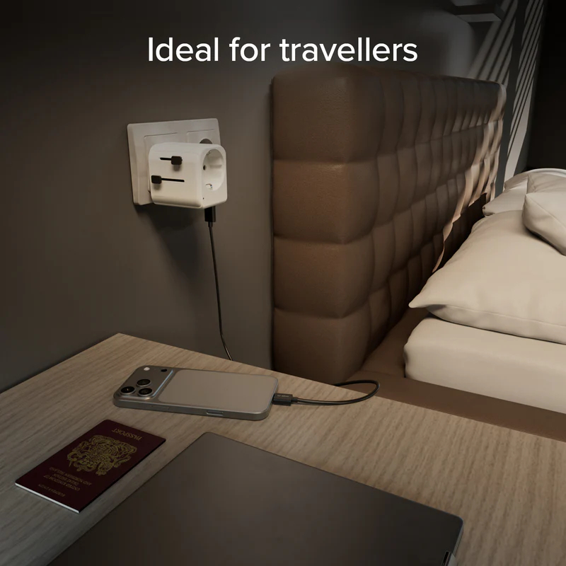 Ein weißer Reiseadapter steckt in einer Steckdose, ein Handy lädt.