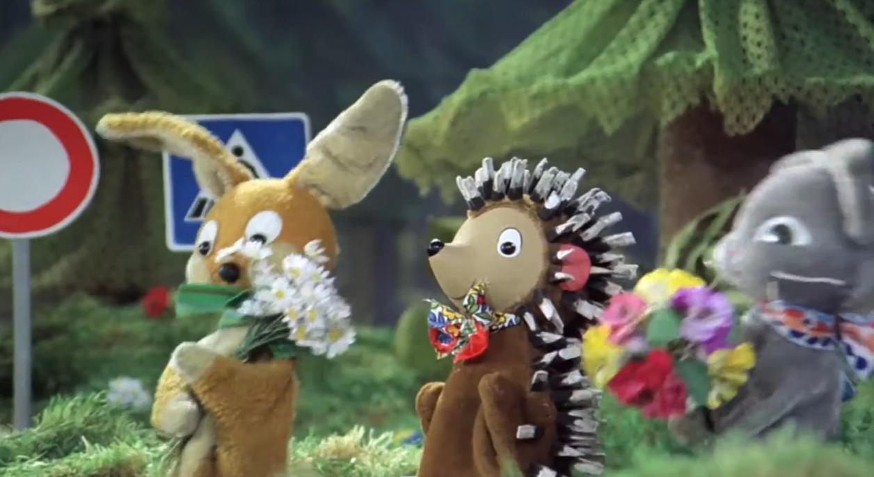 Drei Stofftiere: Hase mit Blumen, Igel mit Blumen, Maus mit Blumen.