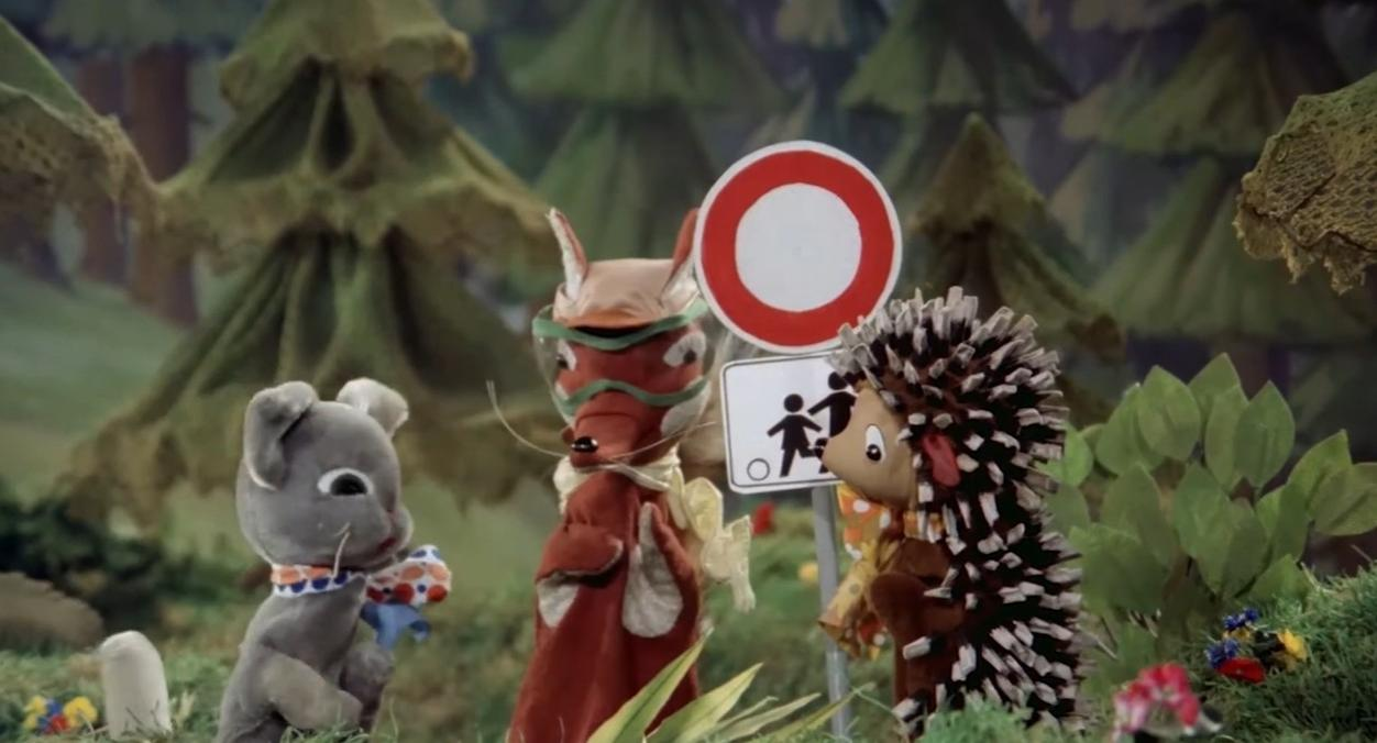 Graue Maus, roter Fuchs und Igel stehen vor Schildern im Wald.