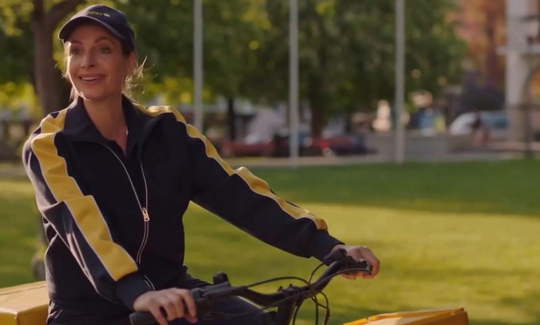 Eine Frau mit Kappe und Trainingsjacke fährt Fahrrad im Freien.