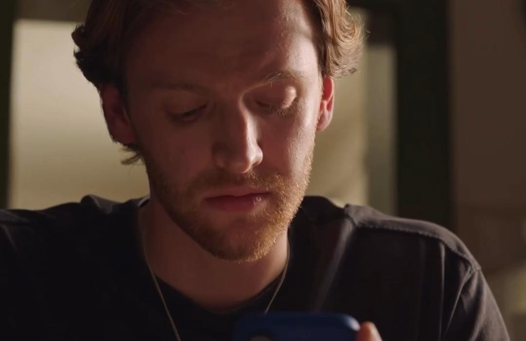 Ein Mann mit Bart schaut auf ein blaues Smartphone.