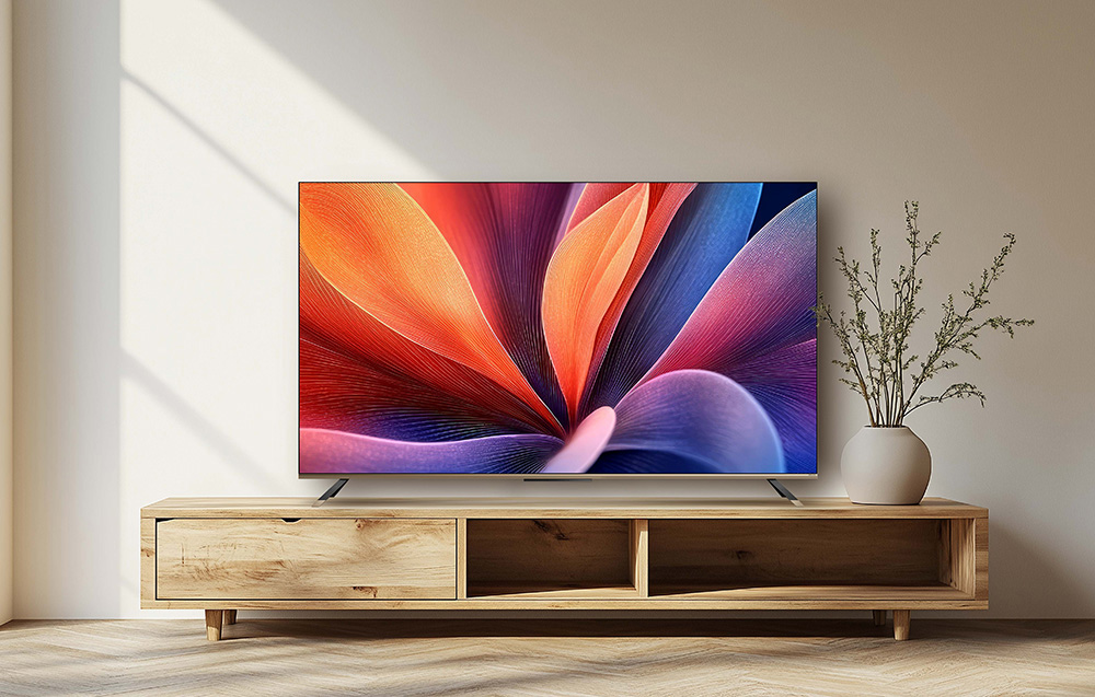 Nowoczesny telewizor wyświetla kolorową sztukę abstrakcyjną na drewnianym stojaku, obok wazonu z gałązkami.