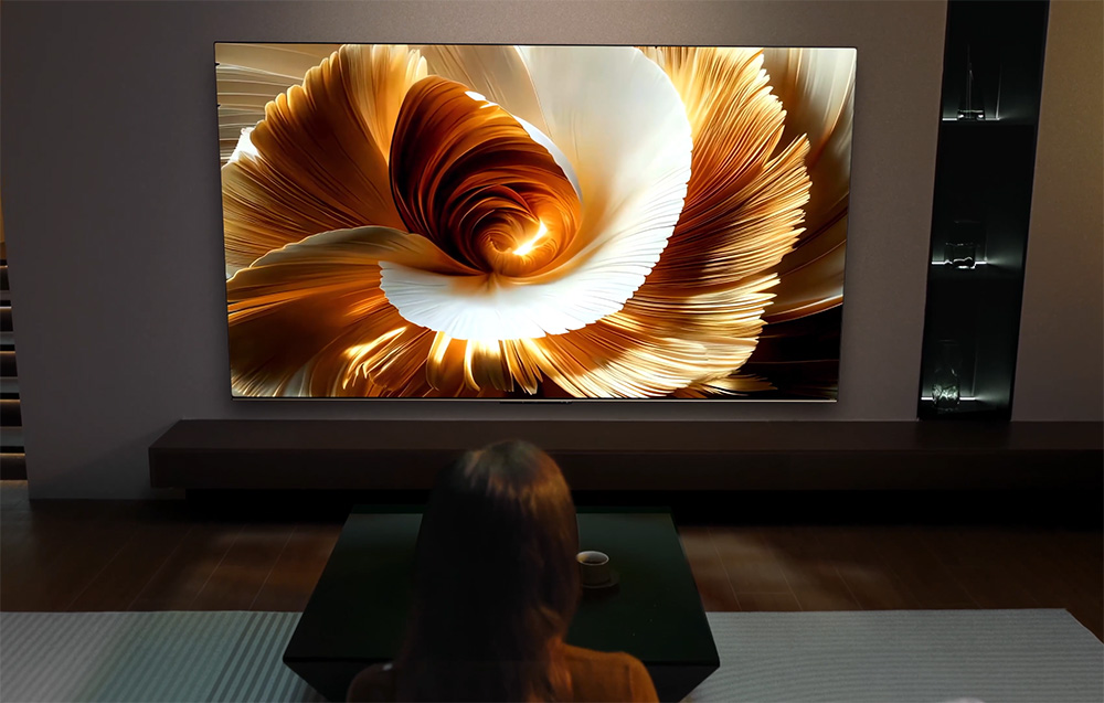 Osoba ogląda duży telewizor wyświetlający abstrakcyjny wzór w kolorze złotym i białym.