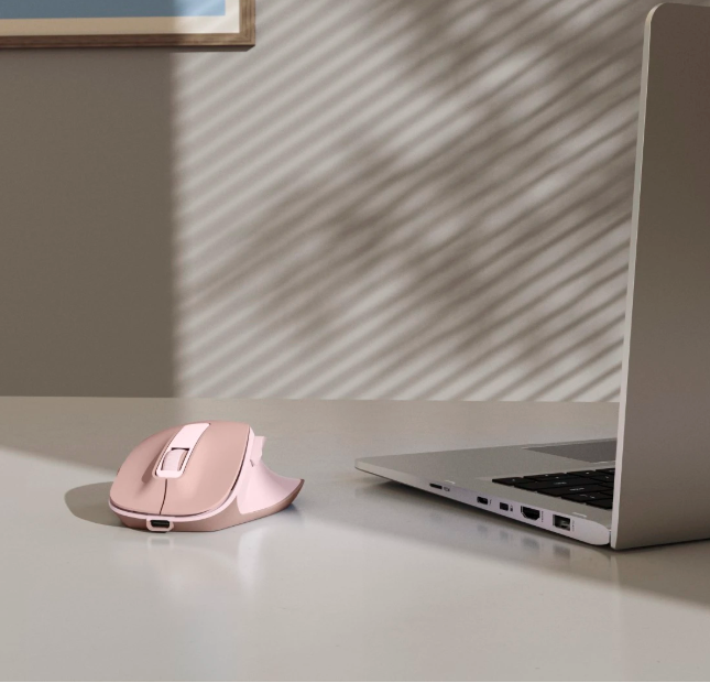 Różowa mysz komputerowa i laptop na biurku.