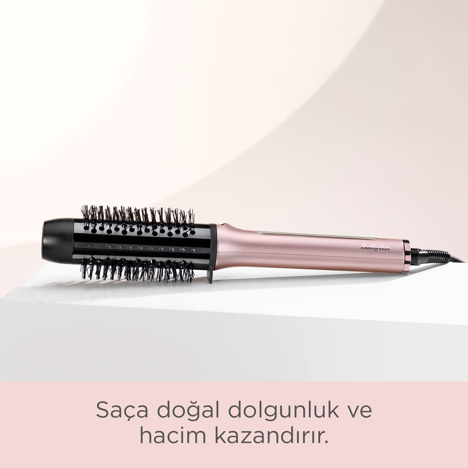 Siyah fırçalı, altın rengi döner saç şekillendirici beyaz zeminde duruyor.
