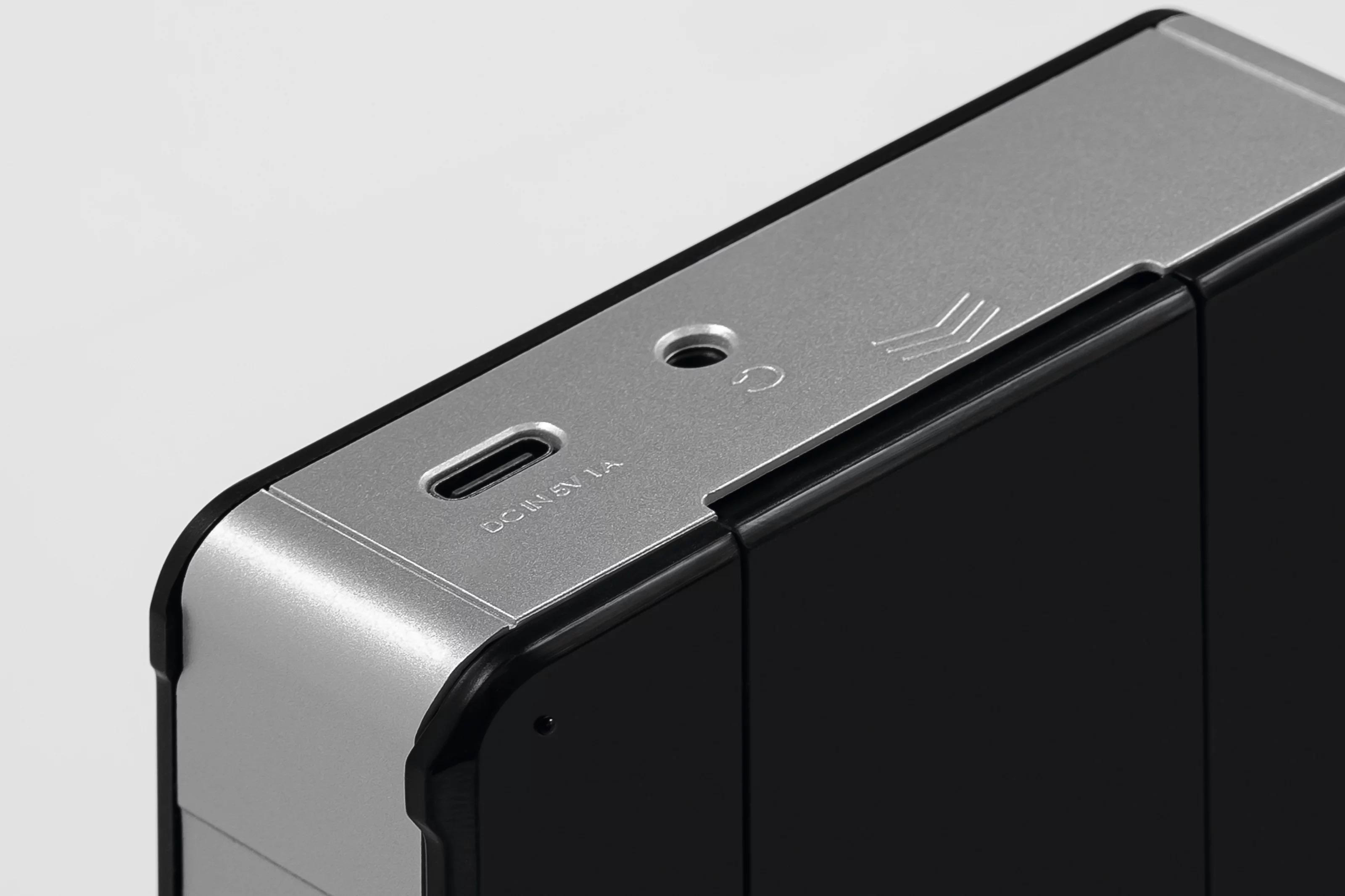 Nahaufnahme einer silbernen USB-C-Buchse und eines Power-Symbols auf einem schwarzen Gerät.