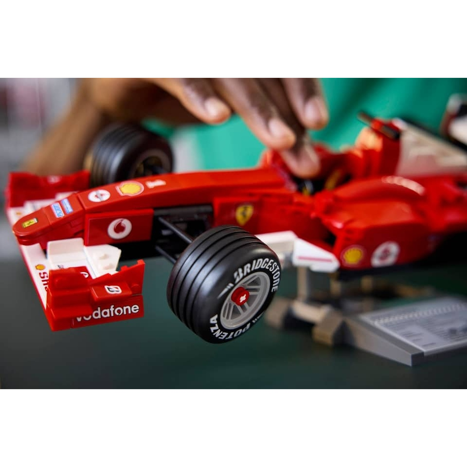 Macchina giocattolo rossa di Formula 1 con marchio Vodafone, tenuta da una mano.