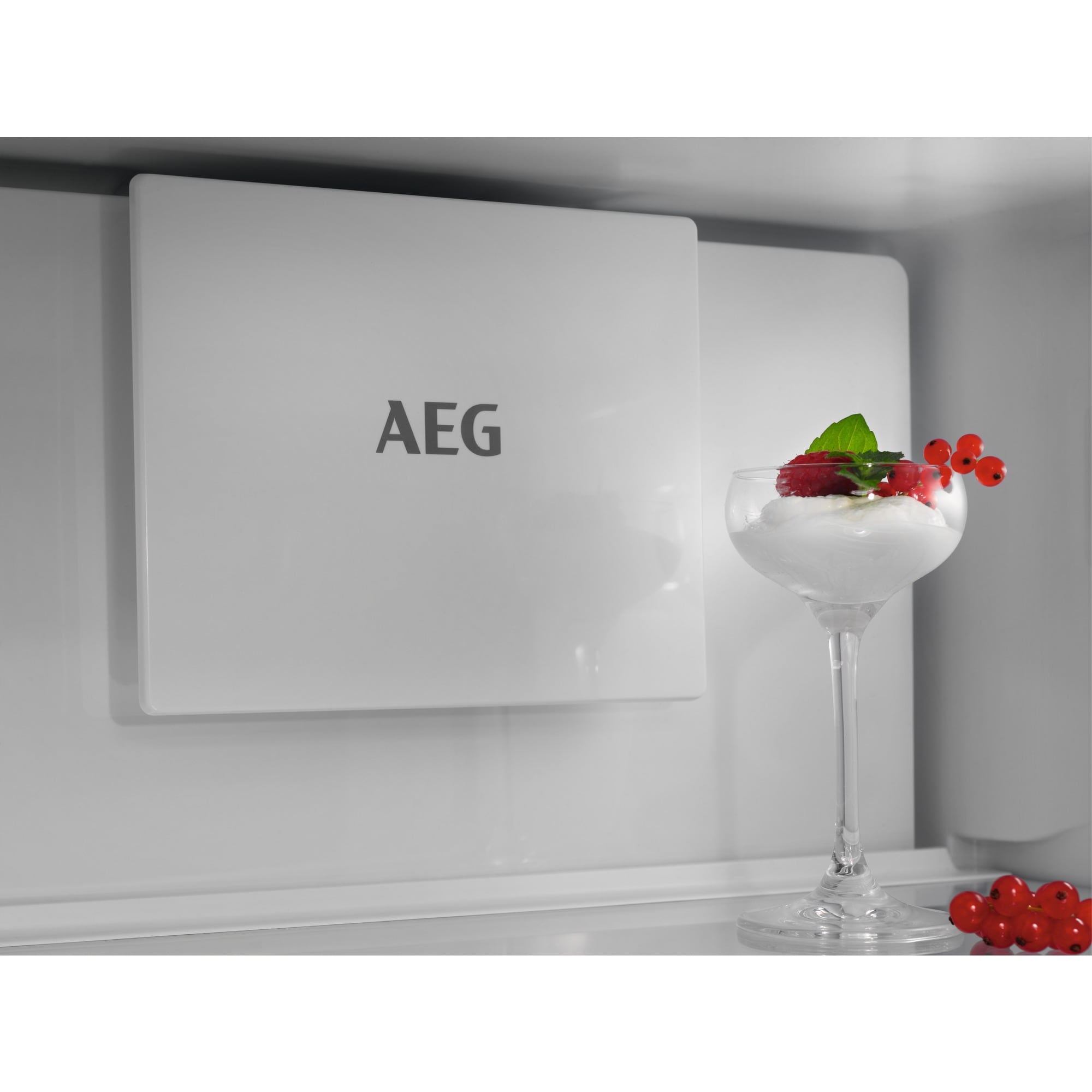 Ein Dessert mit Beeren und Minze in einem Glas, neben dem AEG-Logo auf Weiß.