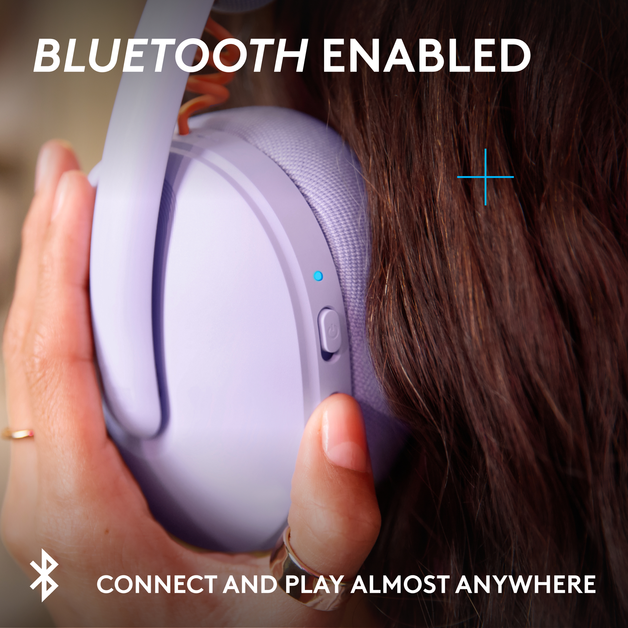 Una mano tiene un auricolare viola con luce blu e pulsante di accensione.