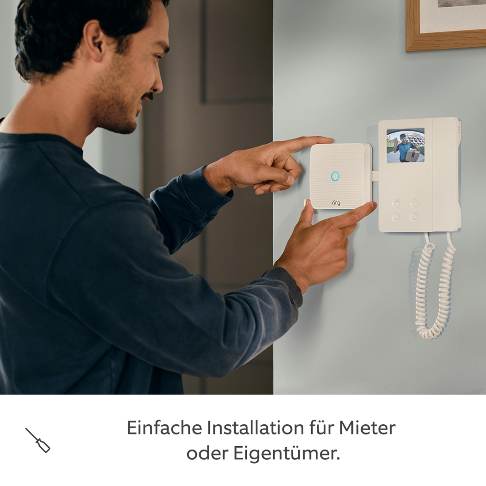 Mann installiert ein weißes Ring-Türsprechmodul an einer hellblauen Wand.