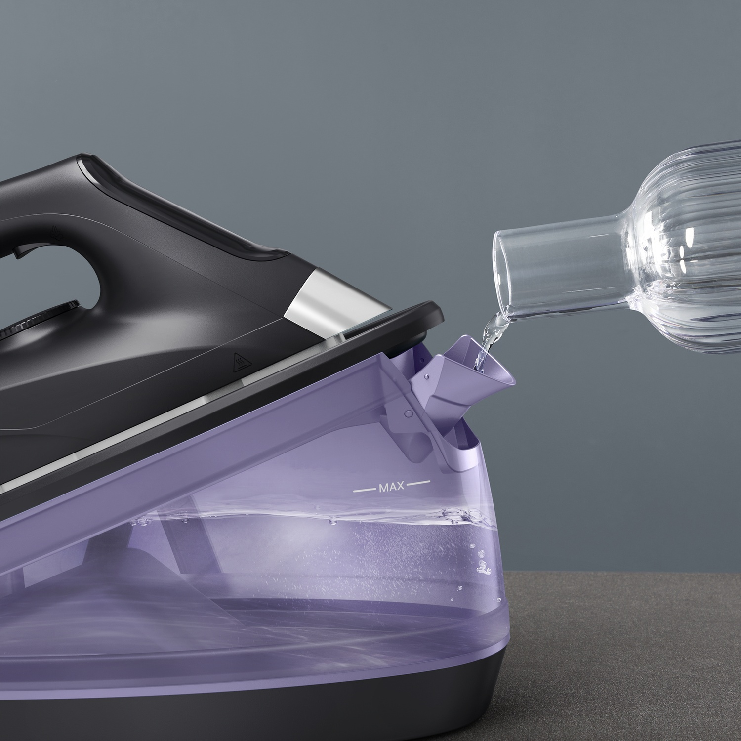 Acqua versata da una bottiglia di vetro nel serbatoio viola di un ferro da stiro.
