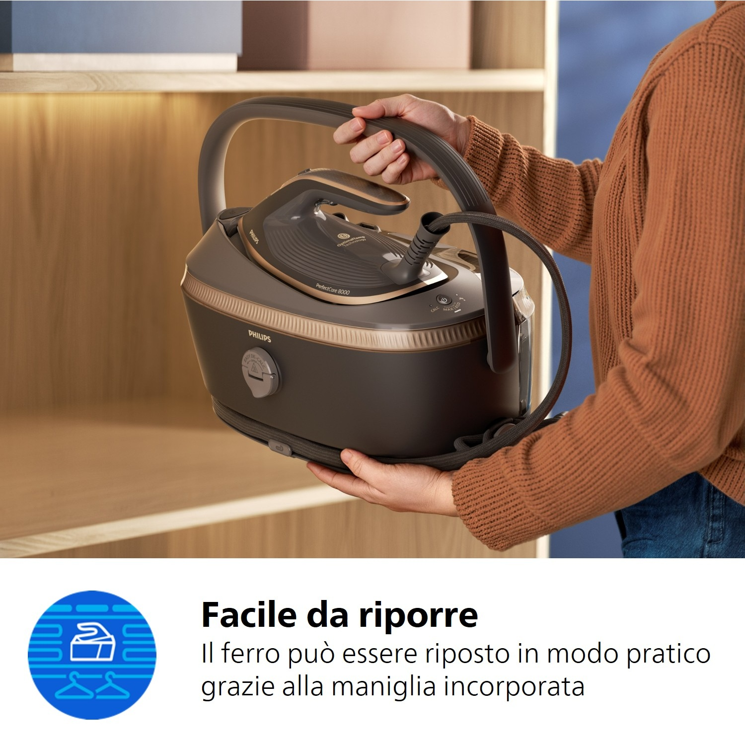 Una persona tiene una stazione ferro da stiro a vapore Philips grigio scuro con accenti dorati.