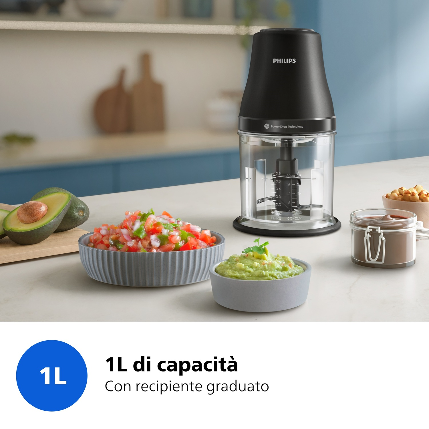 Un tritatutto Philips nero da 1L è su un bancone accanto a ciotole di guacamole e salsa.