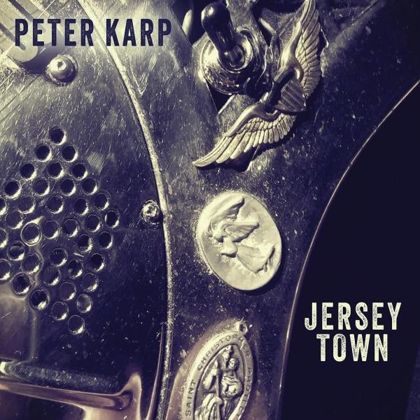 Peter Karp Jersey Town Schriftzug auf Metalloberfläche mit Flügel- und Medaillenapplikationen.