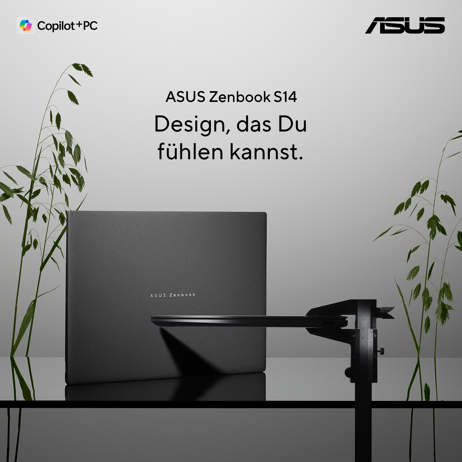 Ein dunkler Asus Zenbook S14 Laptop neben Messwerkzeugen, umgeben von Pflanzen.