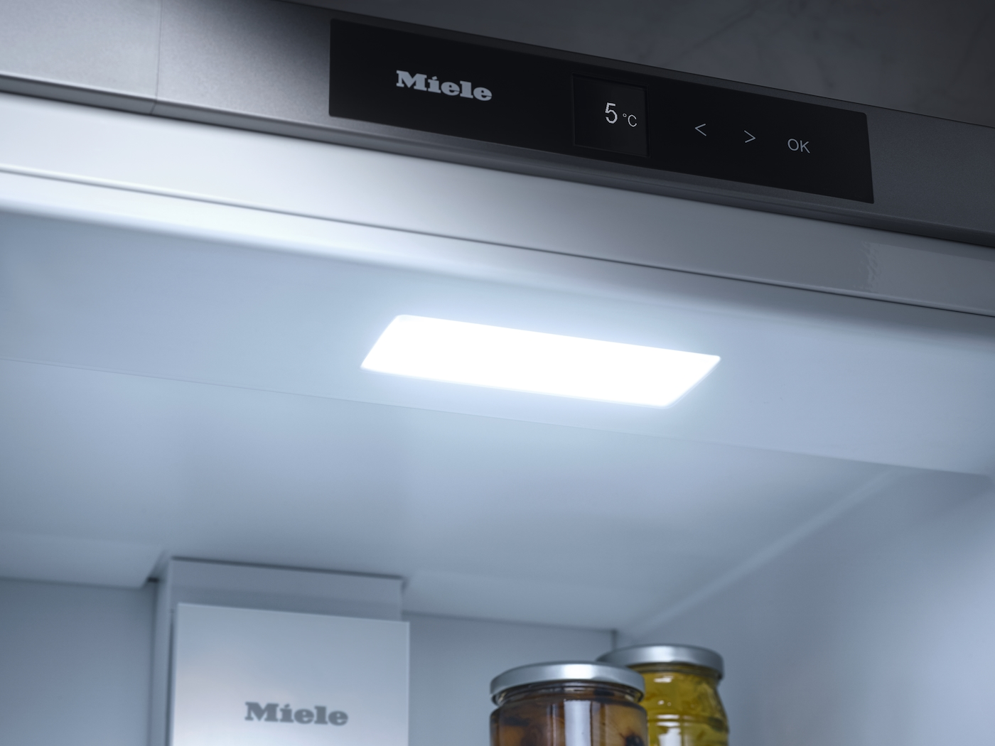 Ein Miele Kühlschrankinnenraum mit beleuchteten Regalen und Gläsern.
