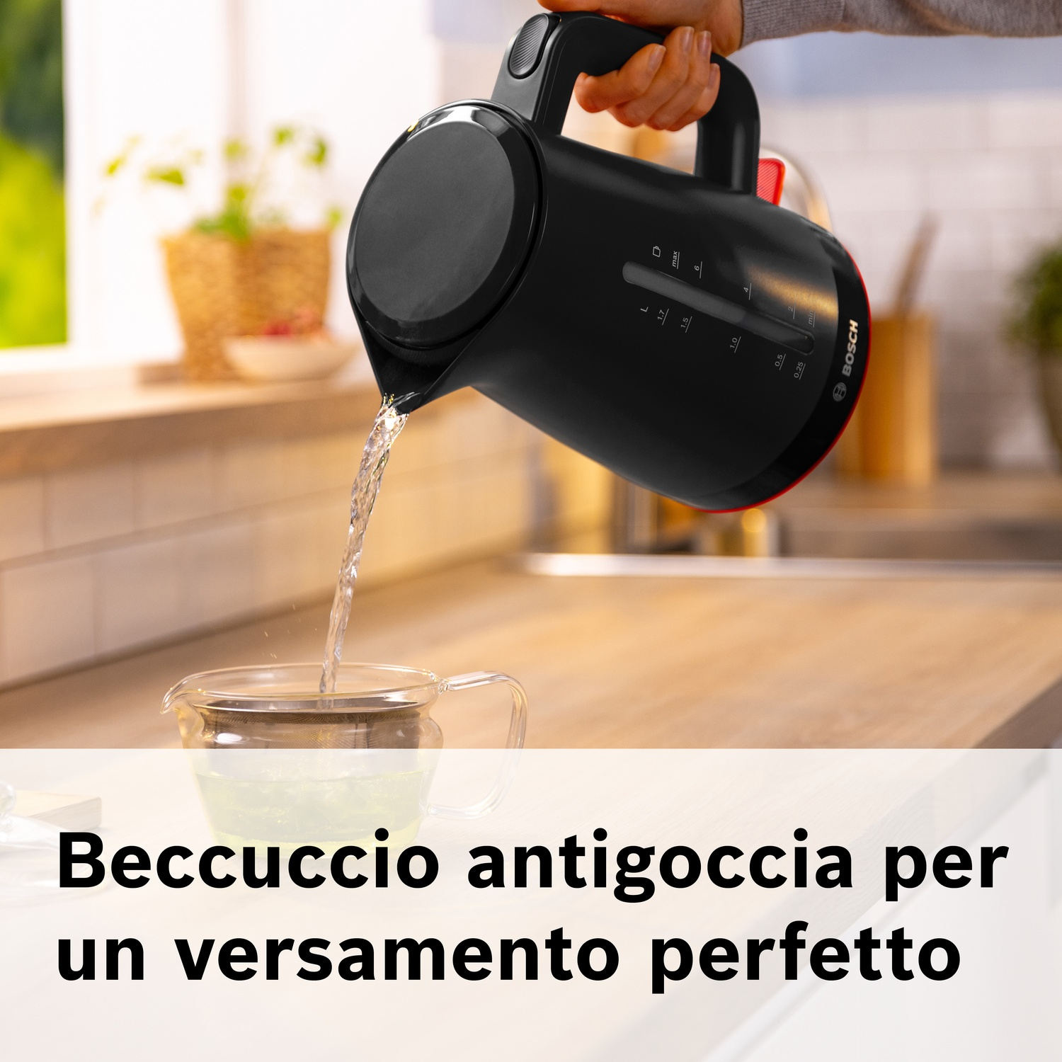 Un bollitore Bosch nero versa acqua in una caraffa di vetro su un piano.