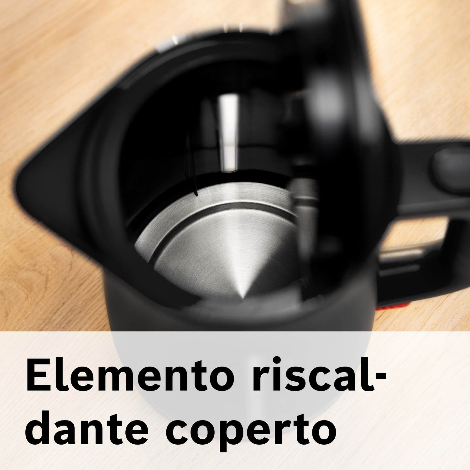 Particolare ravvicinato dell'interno di un bollitore nero con base in metallo su tavolo legno.