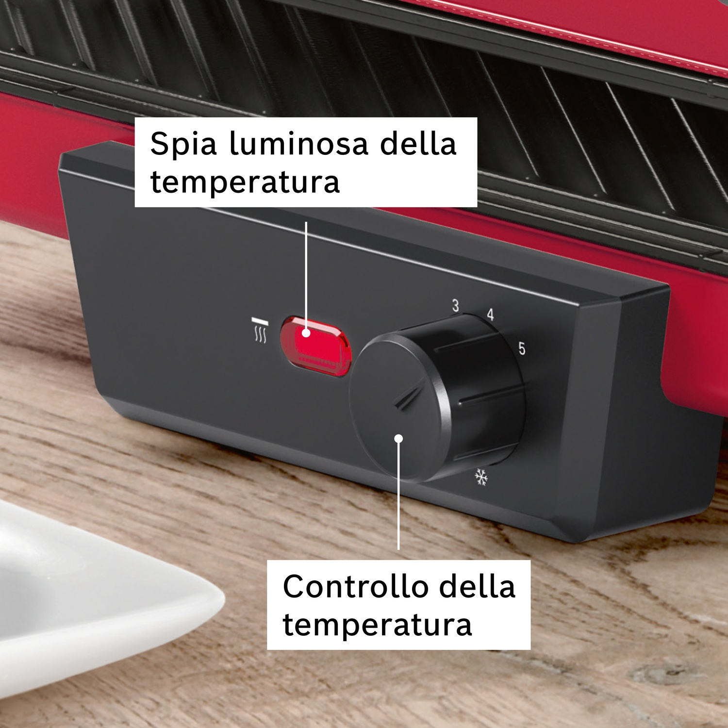 Macchina rossa con manopola nera e spia rossa, accanto una ciotola bianca.