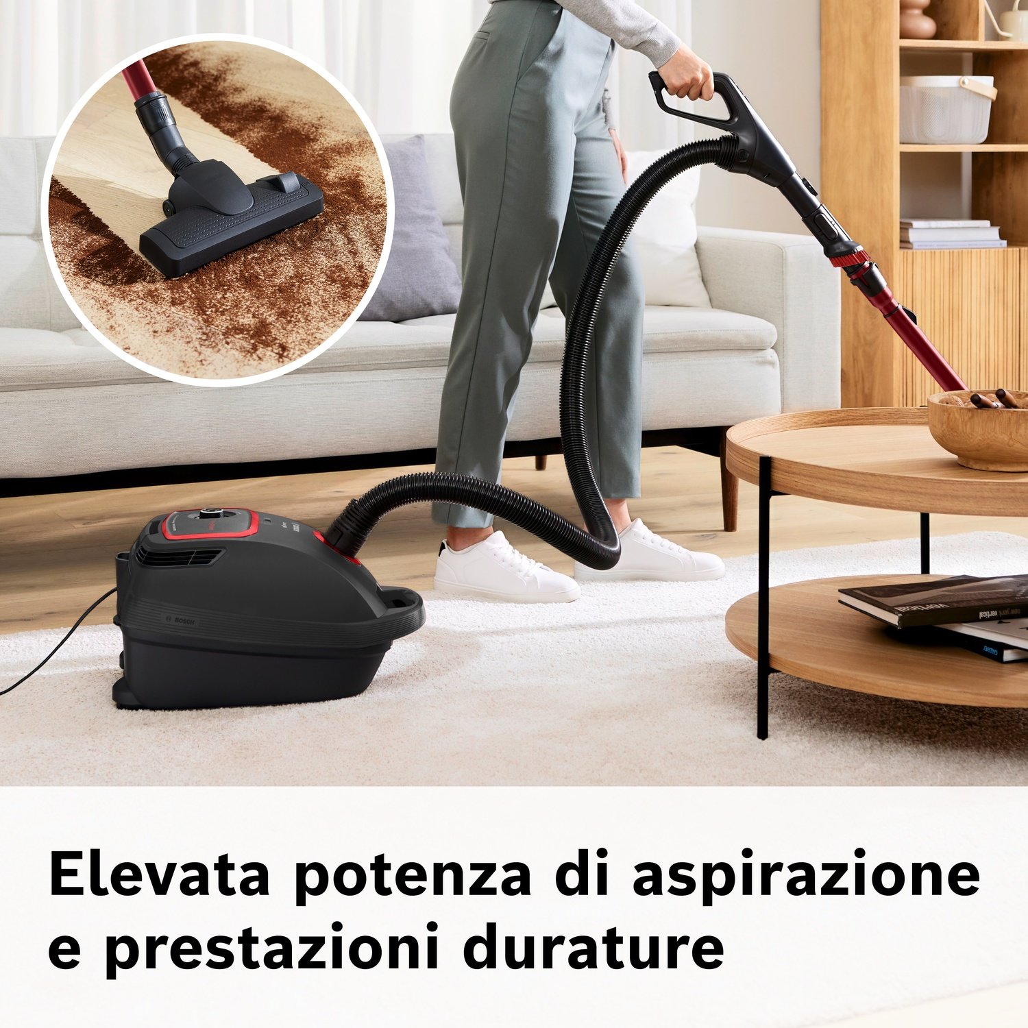 Un aspirapolvere nero pulisce un tappeto mentre una persona lo usa.