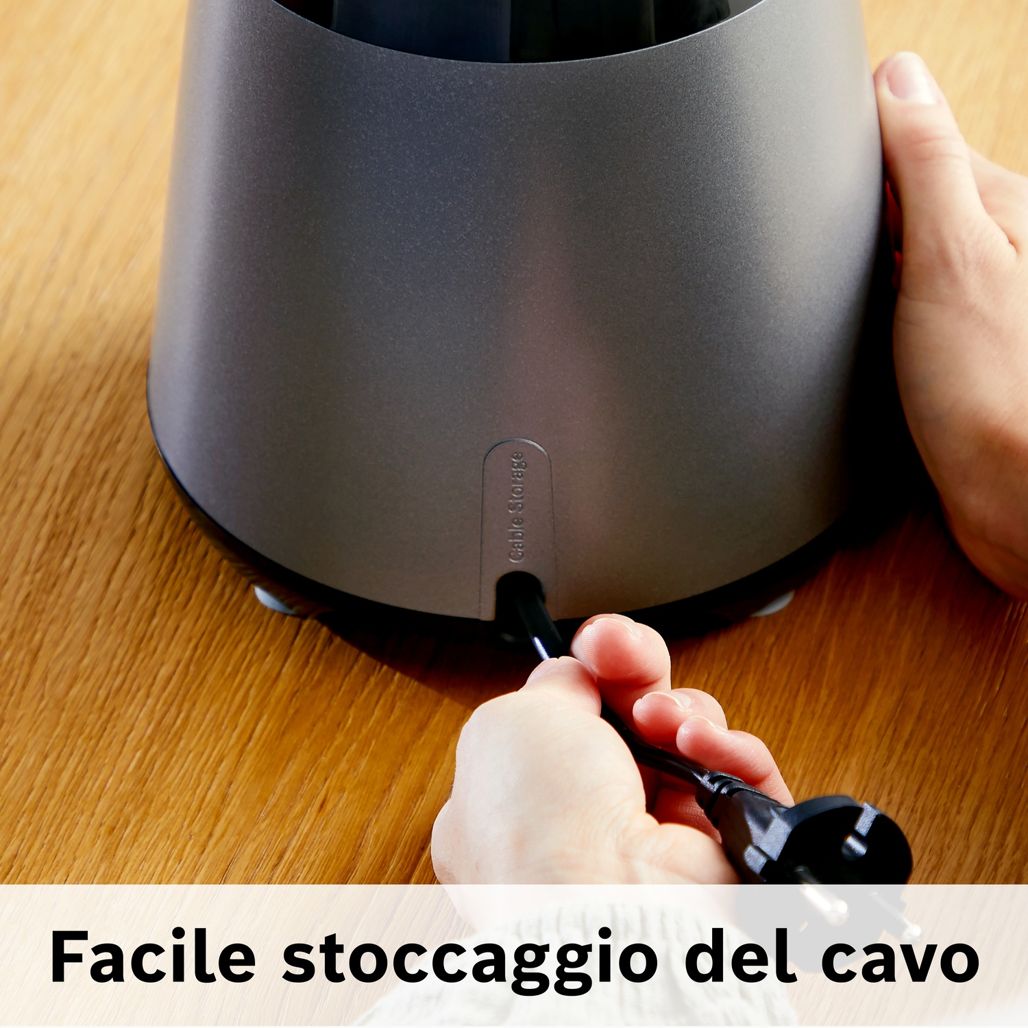 Mani inseriscono un cavo nero in un dispositivo grigio su tavolo legno.