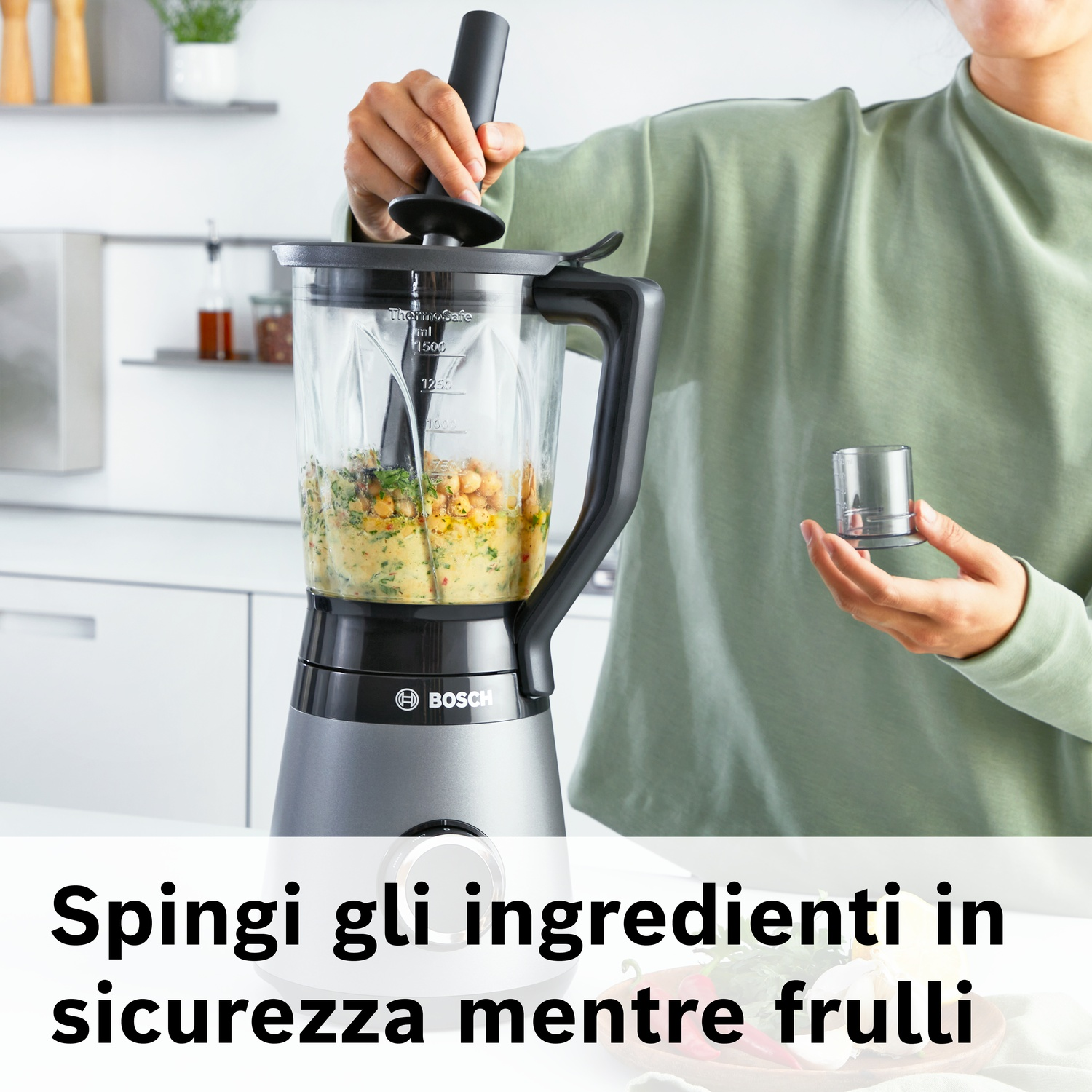 Persona che usa un frullatore con ingredienti e un pestello.