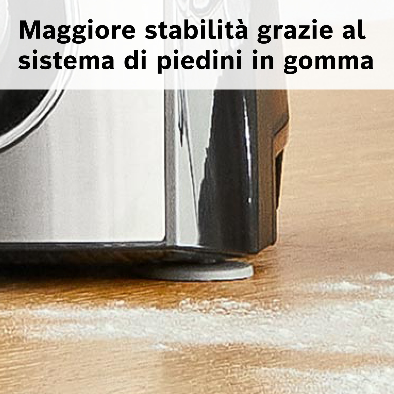 Primo piano del piedino in gomma di un elettrodomestico da cucina su una superficie di legno infarinata, che mostra stabilità.