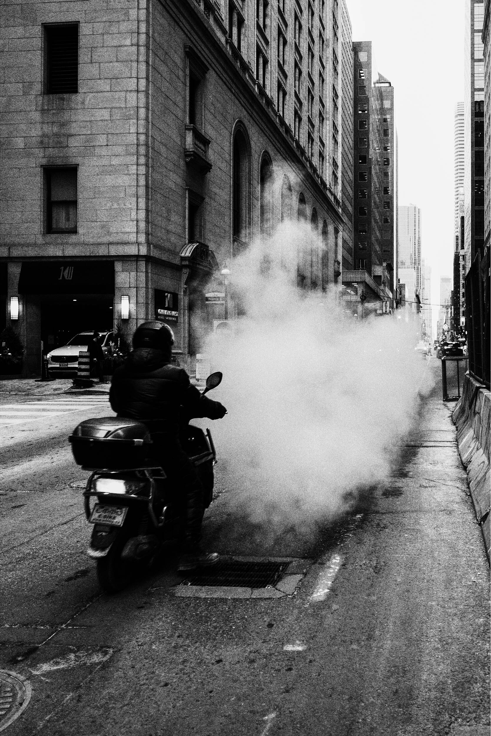 Un motocycliste traverse une épaisse vapeur dans une rue de la ville.