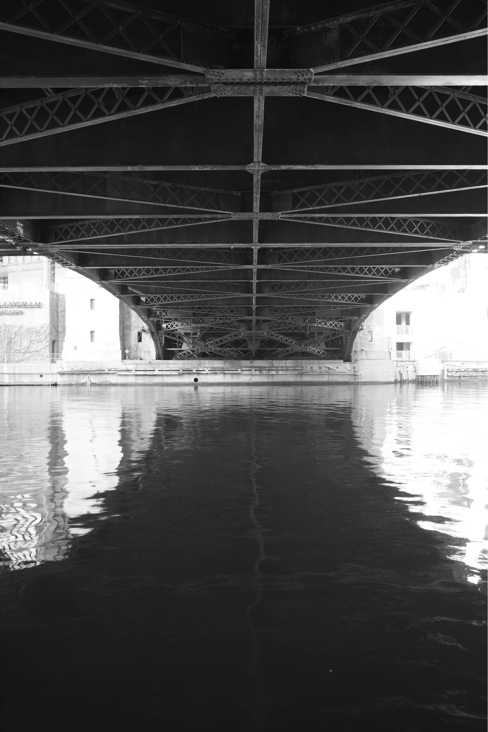 Vue inférieure d'un pont en acier sur l'eau avec reflets.