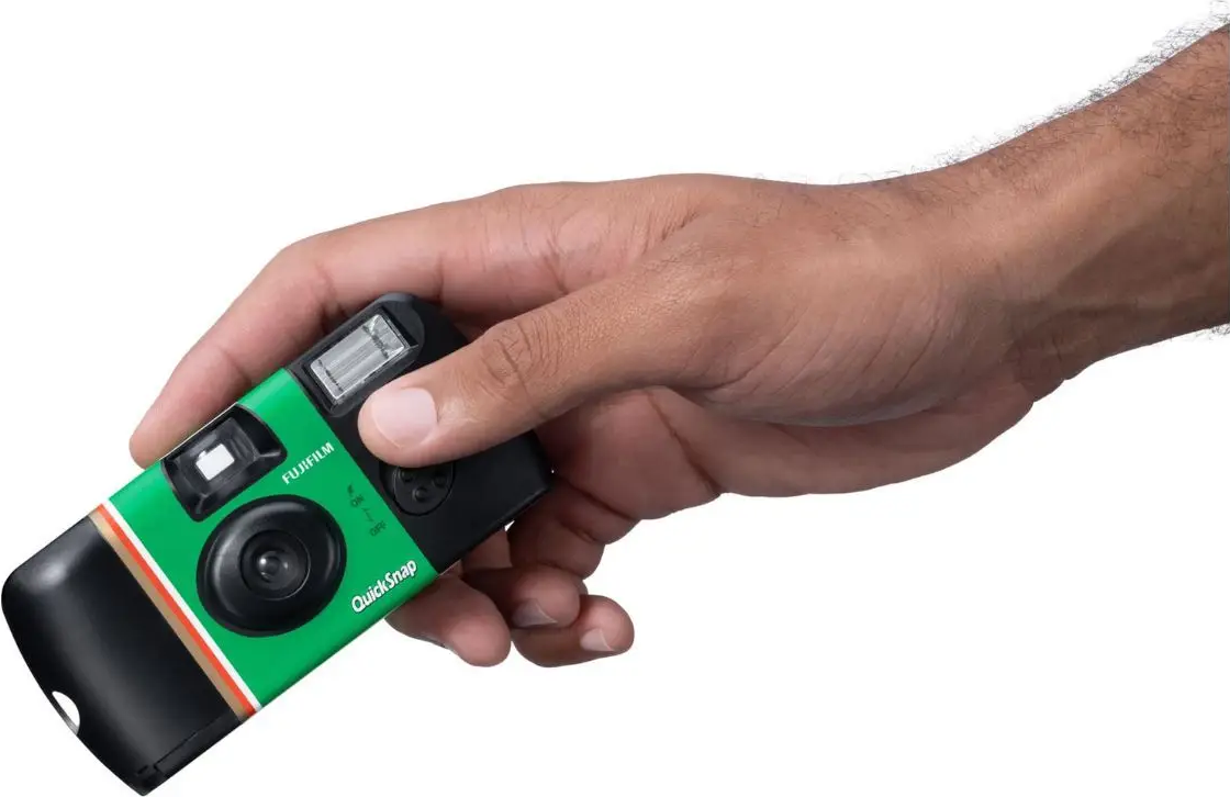 Eine Hand hält eine grüne Fujifilm QuickSnap Kamera mit Blitz.