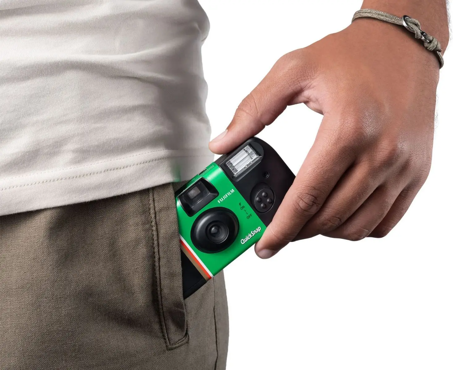 Eine grüne Fujifilm-Kamera wird in eine Hosentasche gesteckt.