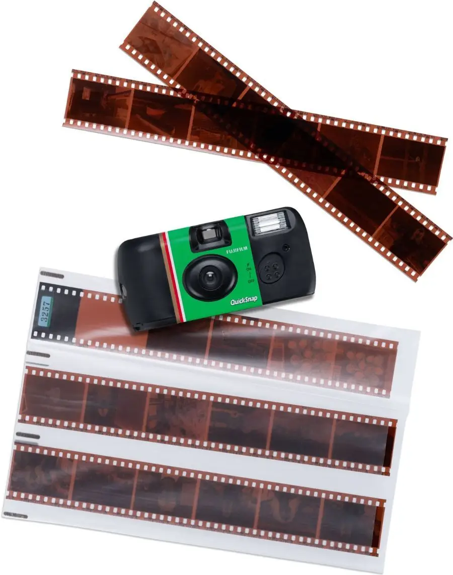 Grüne Einwegkamera mit Filmrollen und Negativen auf weißem Hintergrund.