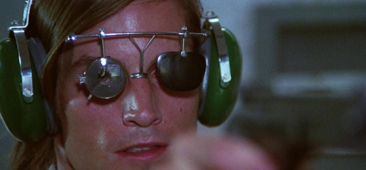 Ein Mann trägt Kopfhörer und eine Schießbrille mit Visier.